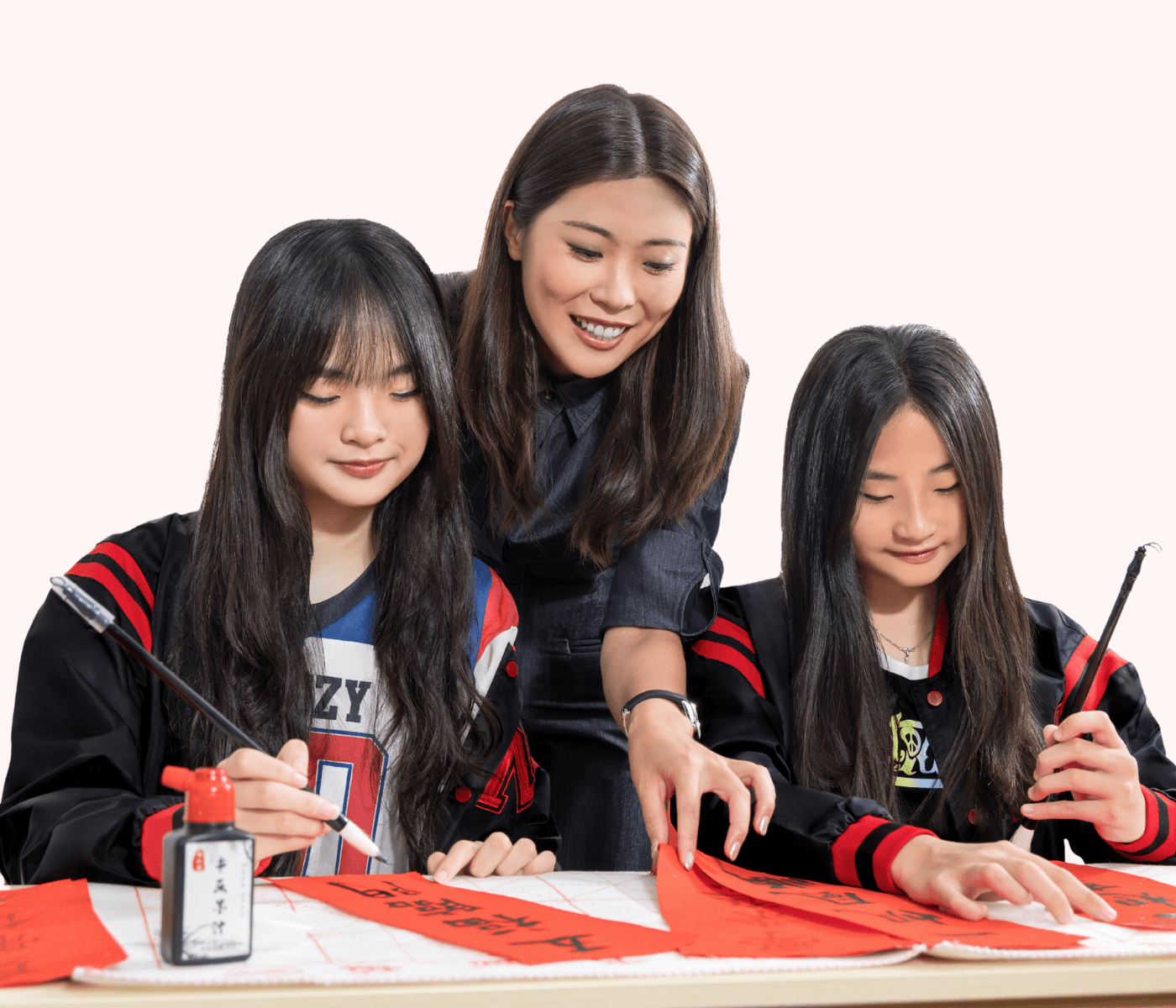 A Mavis tutor guiding two students practising Chinese calligraphy with brush and ink