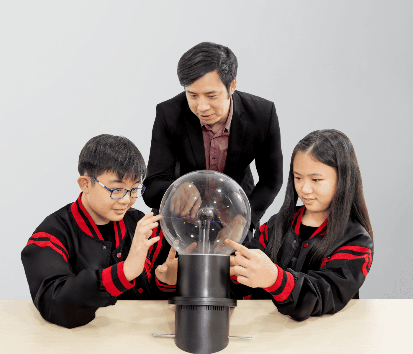 A Mavis tutor and two students examining an electric plasma ball demonstration